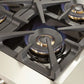 Close-up view of a single sealed burner on the FORNO 48-inch gas range from the 2-Piece Appliance Package, showing the durable cast iron grate, precision flame ring, and stainless steel cooktop surface—engineered for high heat output and responsive cooking control.