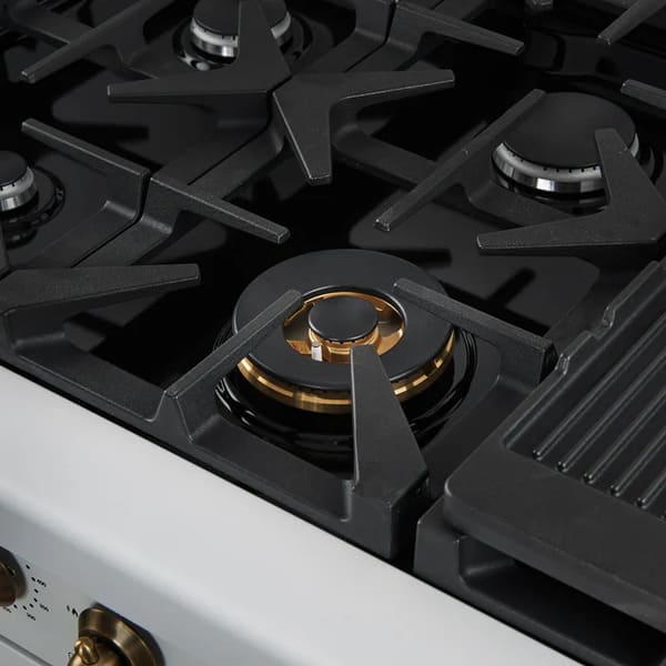 Close-up of a brass burner on the FORNO Antico 48-Inch Dual Fuel Range in white, showing precision flame ports, durable cast iron grates, and a clean stainless steel surface.