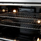 Close-up of the oven interior in the FORNO Galiano 30-Inch French Door Dual Fuel Range in black, featuring a blue enamel finish with stainless steel racks on smooth ball-bearing glides for easy access.