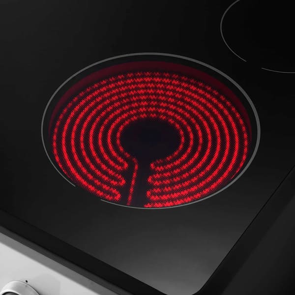 Top view of the FORNO espresso electric range from the 4-Piece Appliance Package with one radiant burner glowing red on the black ceramic glass cooktop, indicating active heating and showcasing precise temperature control in a modern cooking setup.