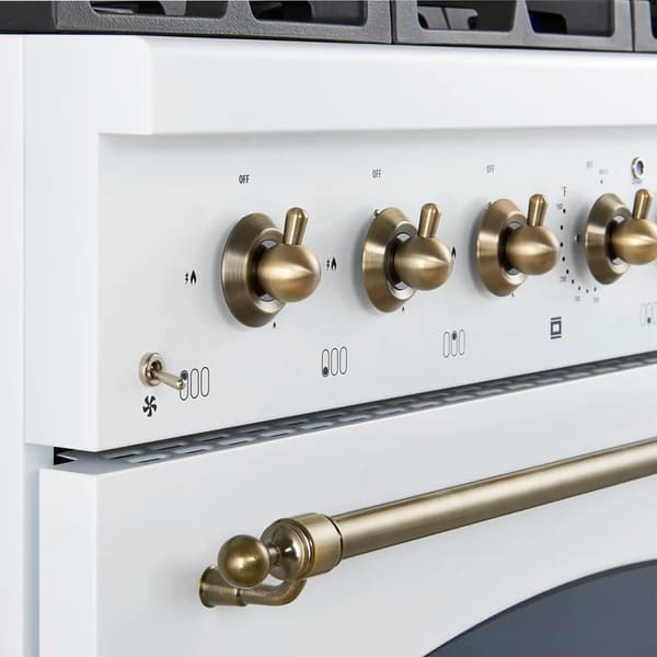 Close-up view of the control knobs on the Forno Antico 36-Inch Dual Fuel Range in white, featuring polished brass bezels, precise temperature markings, and a premium stainless steel panel.