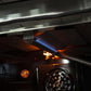 Close-up of a lit broiler burner inside a FORNO gas oven, showing the flame element and convection fan in the oven cavity.