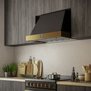 Modern kitchen interior featuring the Forno Vittorio 36-Inch Wall Mount Range Hood with antique brass trim, installed above a stainless steel cooktop. The hood blends seamlessly with white cabinetry and upscale decor, showcasing both functionality and elegant design.